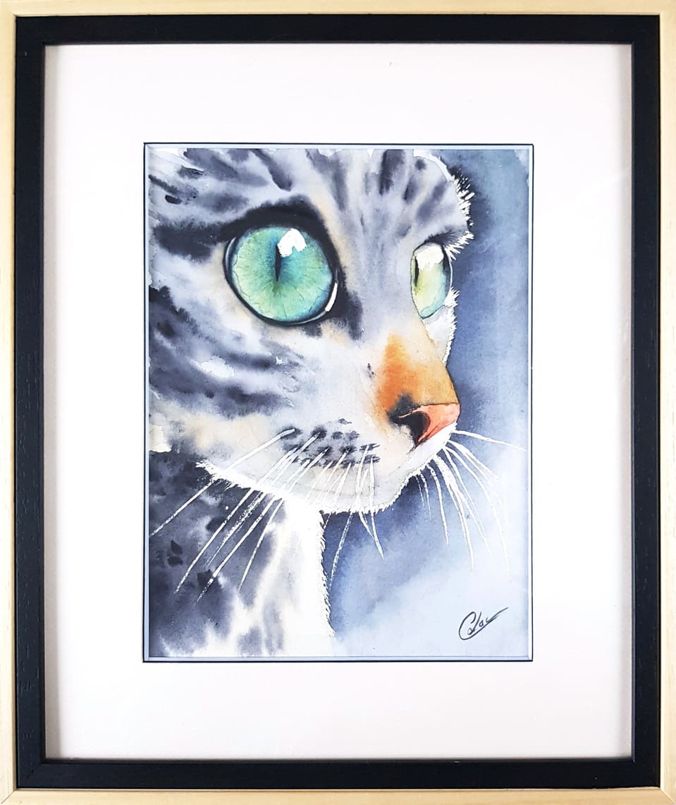 Aquarelle animale représentant un chat gris aux yeux verts en gros plan et son encadrement personnalisé réalisés par Christelle Lachambre artiste-peintre