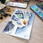 Aquarelle animale représentant un chat gris aux yeux verts en gros plan en cours de réalisation par Christelle Lachambre artiste-peintre