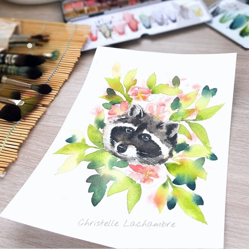 Aquarelle animale représentant un raton-laveur au milieu d'un buisson de fleurs et de branches, en cours de réalisation par Christelle Lachambre artiste-peintre