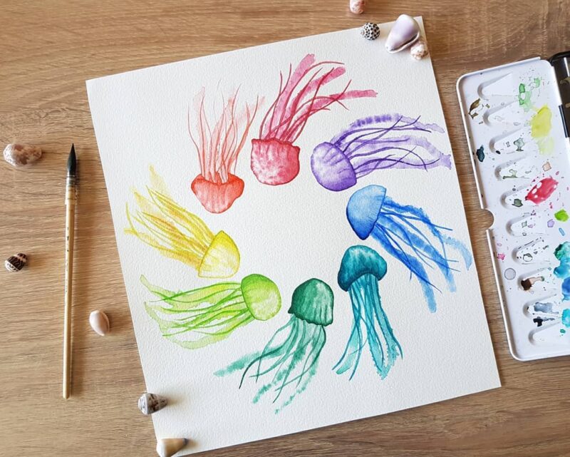 Aquarelle fantastique représentant un cercle de méduses dansant autour du centre, chaque méduse porte une couleur différente, le tout représentant un cercle chromatiques en cours de réalisation par Christelle Lachambre artiste-peintre