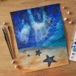 Aquarelle fantastique illustration d'une galaxie dans la mer avec des étoiles de mer disposées sur le sable en cours de réalisation par Christelle Lachambre artiste-peintre