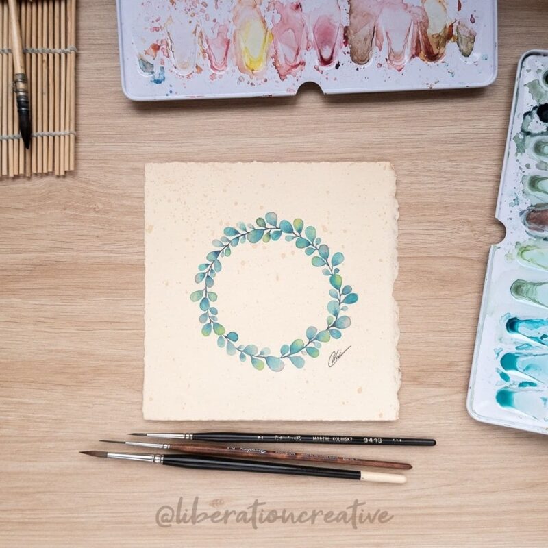 Aquarelle fantastique représentant une couronne végétale dans les tonalités bleu turquoise sur un papier teinté en cours de réalisation par Christelle Lachambre artiste-peintre