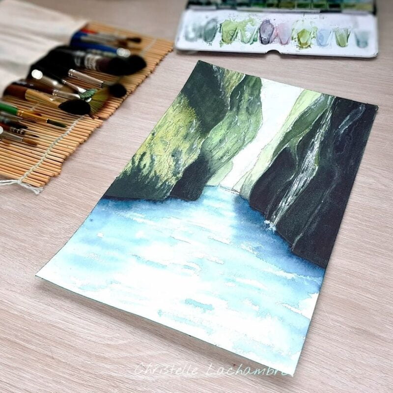 Aquarelle paysage représentant une rivière qui coule entre des falaises recouvertes de mousses verte en cours de réalisation par Christelle Lachambre artiste-peintre