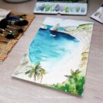 Aquarelle paysage représentant une plage entourée de falaises en cours de réalisation par Christelle Lachambre artiste-peintre