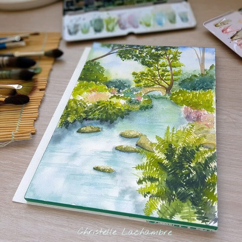 Aquarelle paysage représentant une rivière sous les arbres, passant sous un pont en pierre en cours de réalisation par Christelle Lachambre artiste-peintre