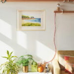 Aquarelle originale Maison au bord de la mer encadrée en décoration intérieure sur le mur d'un salon à la décoration bohème