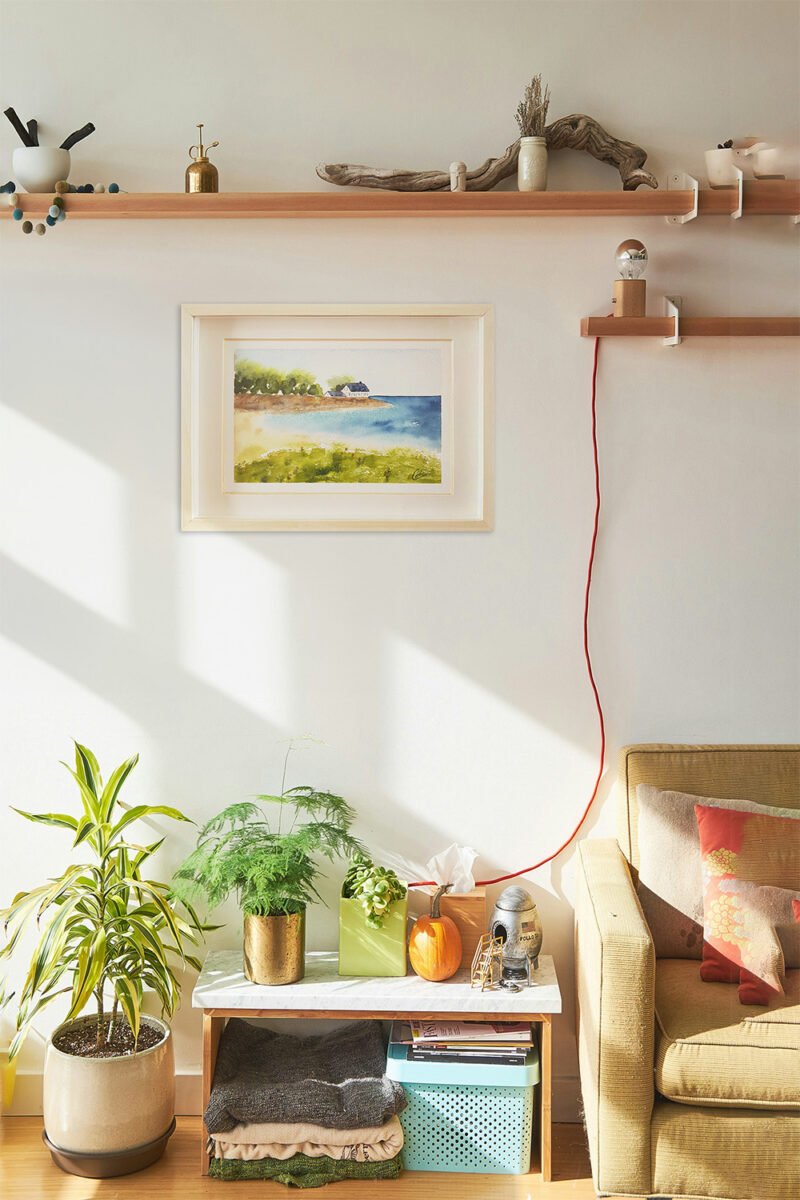 Aquarelle originale Maison au bord de la mer encadrée en décoration intérieure sur le mur d'un salon à la décoration bohème
